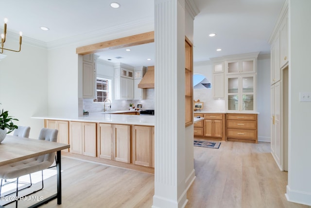 kitchen featuring kitchen peninsula, decorative backsplash, premium range hood, light brown cabinetry, and light wood-type flooring