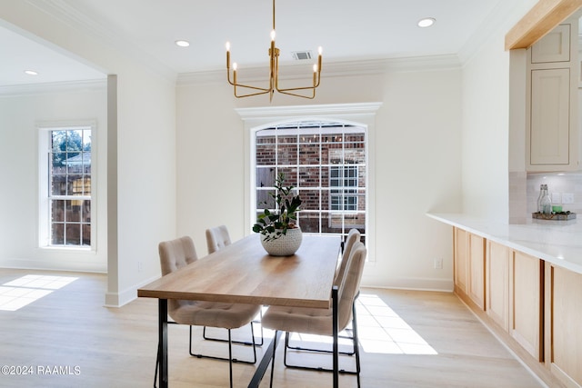 dining space featuring ornamental molding, a notable chandelier, and light hardwood / wood-style floors