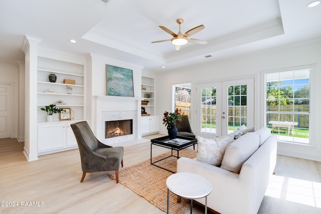 living room with light hardwood / wood-style flooring, french doors, a tray ceiling, and built in shelves