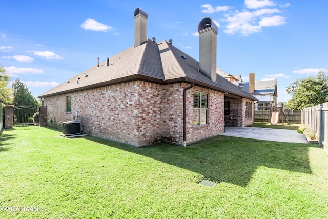 rear view of house featuring central AC unit, a lawn, and a patio area