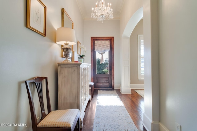 doorway to outside featuring a notable chandelier, crown molding, and dark wood-type flooring