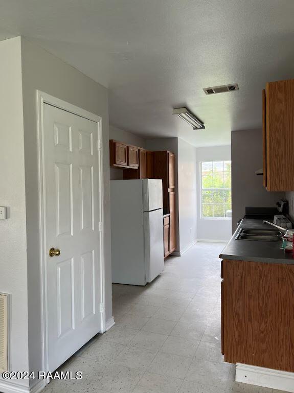 kitchen featuring white refrigerator, sink, and a textured ceiling