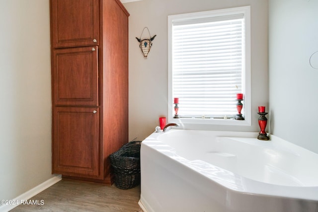 bathroom featuring hardwood / wood-style floors, plenty of natural light, and a washtub