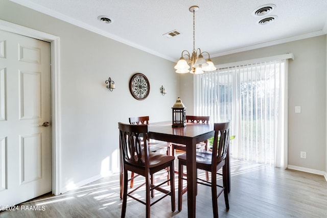 dining space featuring a notable chandelier, light wood-type flooring, crown molding, and a textured ceiling