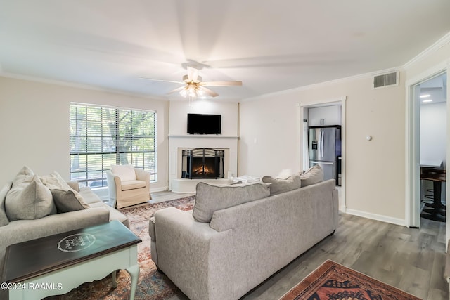 living area featuring ornamental molding, a ceiling fan, visible vents, and wood finished floors