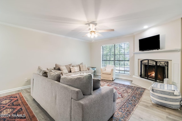 living area featuring wood finished floors, ceiling fan, and ornamental molding