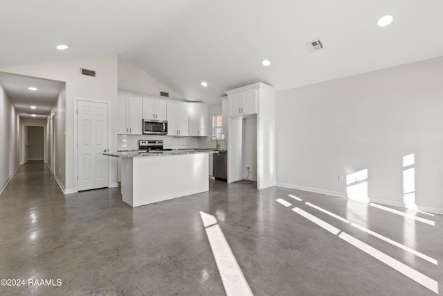 kitchen featuring decorative backsplash, appliances with stainless steel finishes, light stone countertops, a center island, and white cabinetry