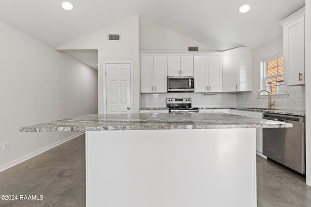 kitchen with vaulted ceiling, stainless steel appliances, a kitchen island, and white cabinetry