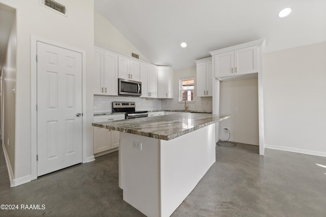 kitchen featuring lofted ceiling, stone counters, white cabinets, appliances with stainless steel finishes, and a kitchen island