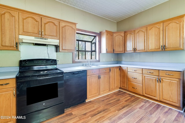 kitchen featuring black appliances, sink, and light wood-type flooring