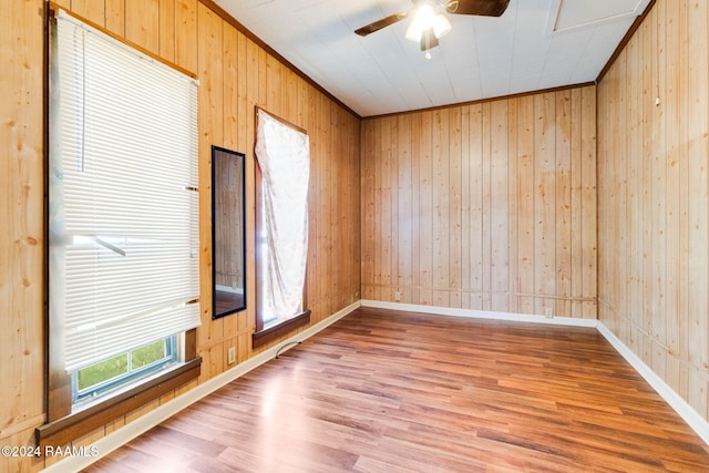 unfurnished room with ceiling fan, wood walls, wood-type flooring, and ornamental molding