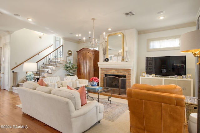 living room featuring a brick fireplace, an inviting chandelier, light hardwood / wood-style flooring, and crown molding