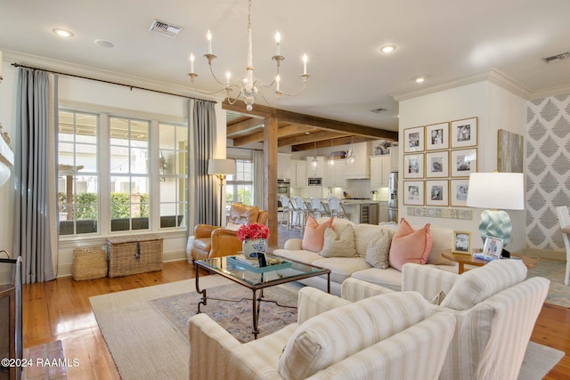 living room with light wood-type flooring, crown molding, and a chandelier