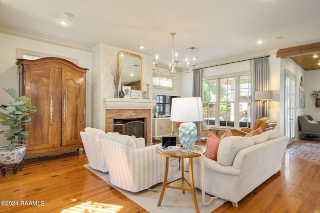 living room featuring a fireplace, a chandelier, light hardwood / wood-style floors, and crown molding