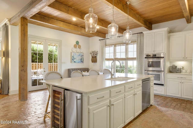 kitchen with a kitchen bar, an island with sink, white cabinets, and sink