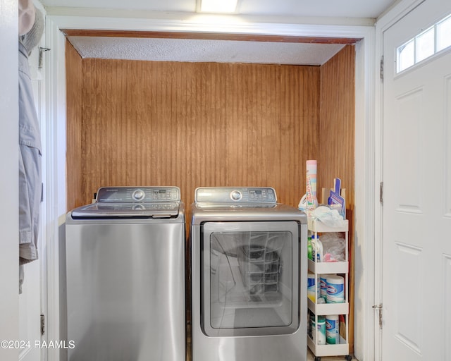 laundry area with independent washer and dryer, a textured ceiling, and wood walls