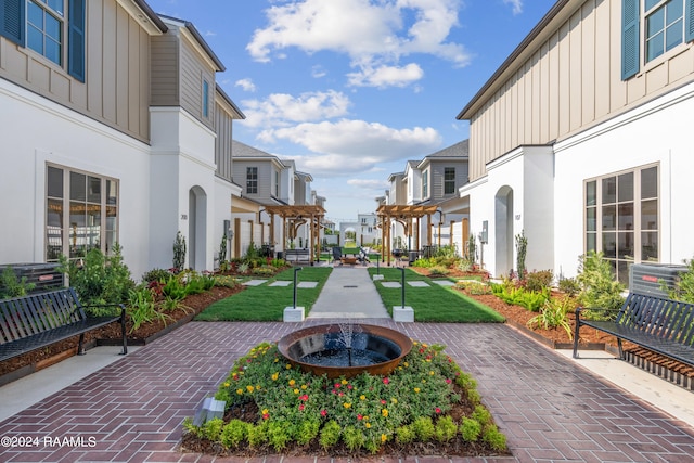 view of home's community with a pergola, a patio area, and a lawn