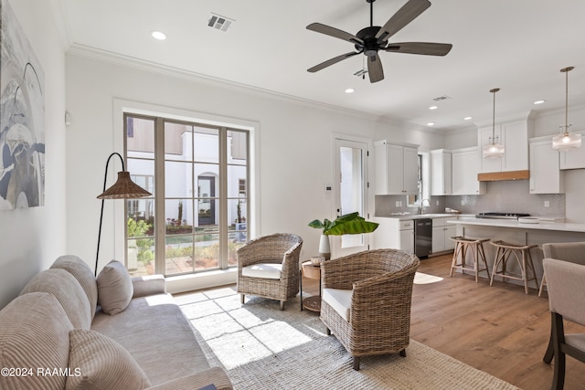 living room featuring light hardwood / wood-style floors, ornamental molding, and ceiling fan