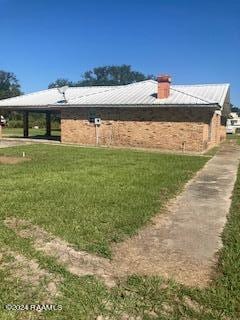 view of home's exterior with a lawn, a carport, a chimney, and metal roof