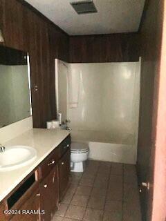 bathroom with toilet, vanity, and tile patterned flooring