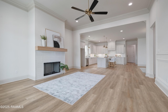 living area with ornamental molding, a fireplace, and light wood-style floors