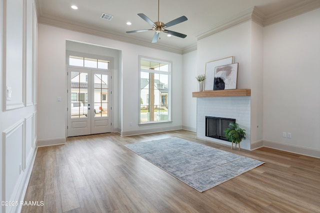 doorway to outside with visible vents, baseboards, light wood-style flooring, crown molding, and a brick fireplace