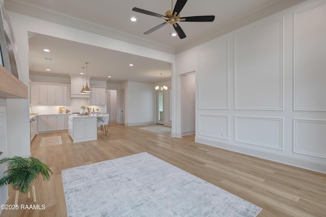 unfurnished living room featuring ornamental molding, light wood-style floors, and a decorative wall