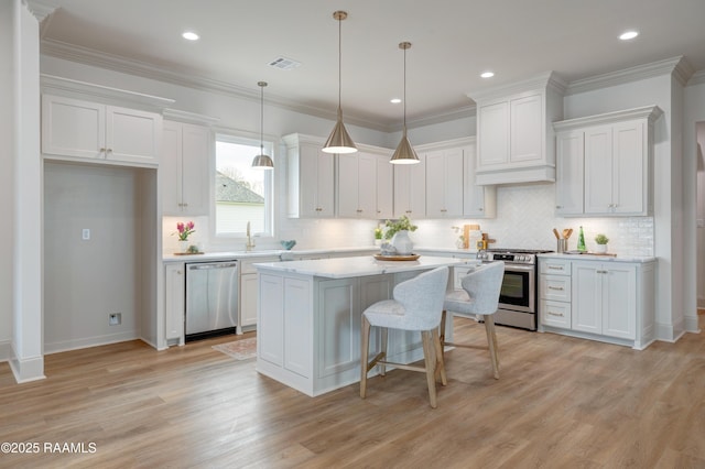 kitchen with stainless steel appliances, a center island, light countertops, and white cabinetry