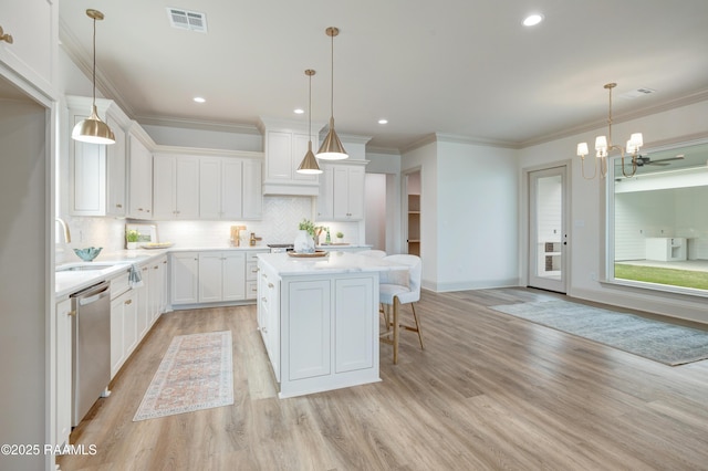 kitchen with light countertops, stainless steel dishwasher, a center island, and white cabinets