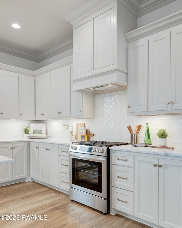 kitchen featuring light wood-style flooring, white cabinetry, light countertops, stainless steel gas range, and crown molding