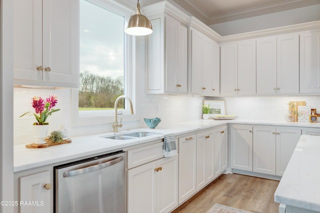 kitchen featuring crown molding, stainless steel dishwasher, white cabinetry, pendant lighting, and a sink