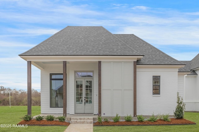 exterior space with roof with shingles and a front lawn