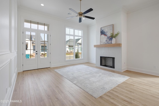 interior space with a fireplace, crown molding, recessed lighting, light wood-style flooring, and baseboards