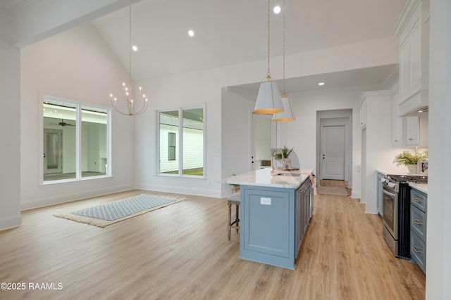 kitchen featuring stainless steel range with gas cooktop, white cabinetry, pendant lighting, and a breakfast bar area