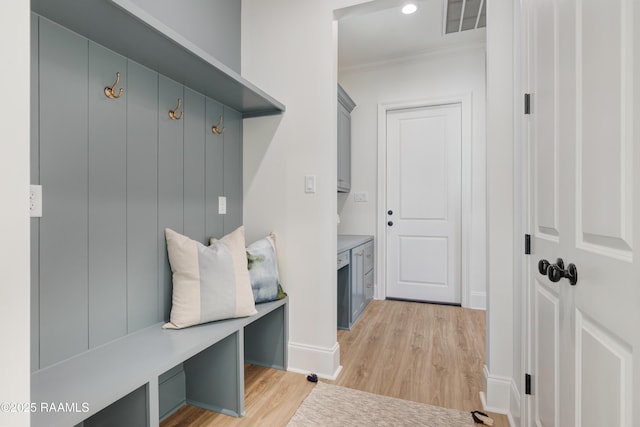 mudroom featuring ornamental molding, light wood finished floors, visible vents, and baseboards