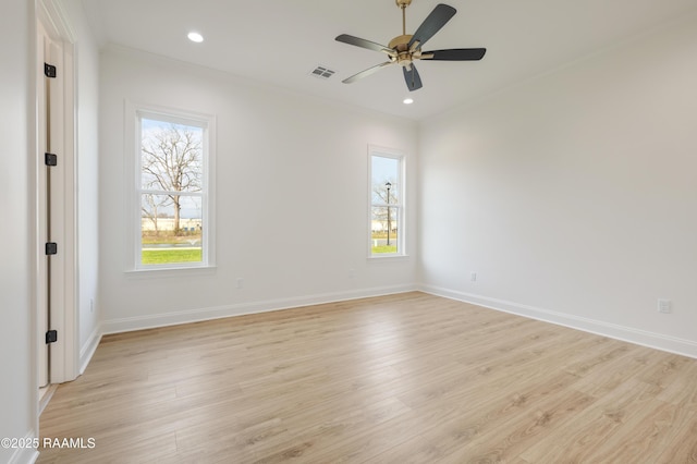 empty room with a wealth of natural light, visible vents, and crown molding