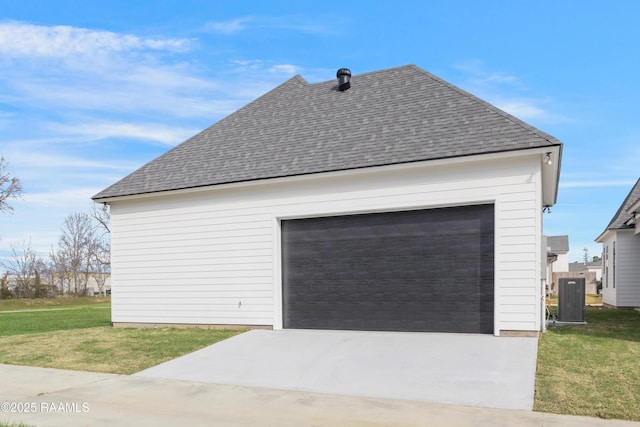 view of side of property with a detached garage, central AC unit, a lawn, and roof with shingles