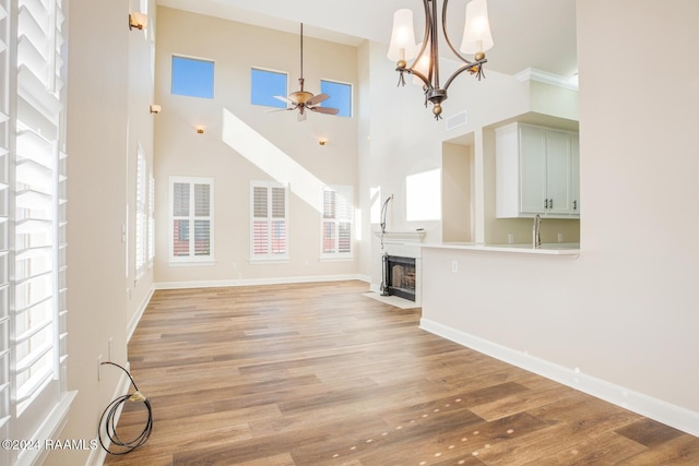 201 Settlers Trace Blvd Unit 2401, Lafayette, LA 70508 - unfurnished living room featuring a ceiling fan, healthy amount of natural light, a fireplace with flush hearth, a high ceiling, and light wood-type flooring