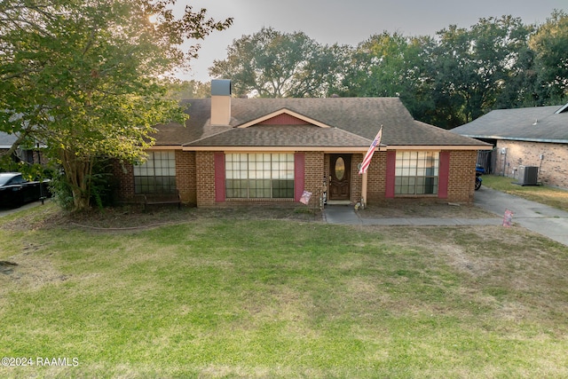 ranch-style home with a front lawn and central AC unit