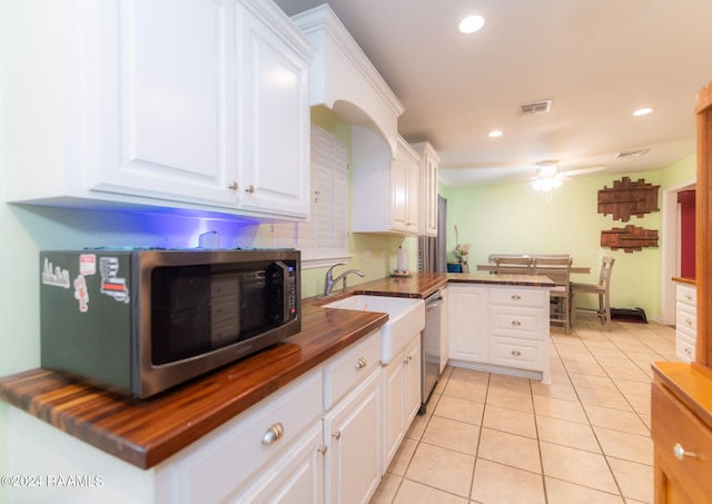 kitchen with kitchen peninsula, ceiling fan, white cabinetry, stainless steel appliances, and butcher block countertops