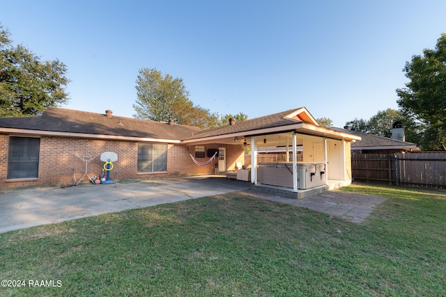 back of house with a patio, a hot tub, and a lawn