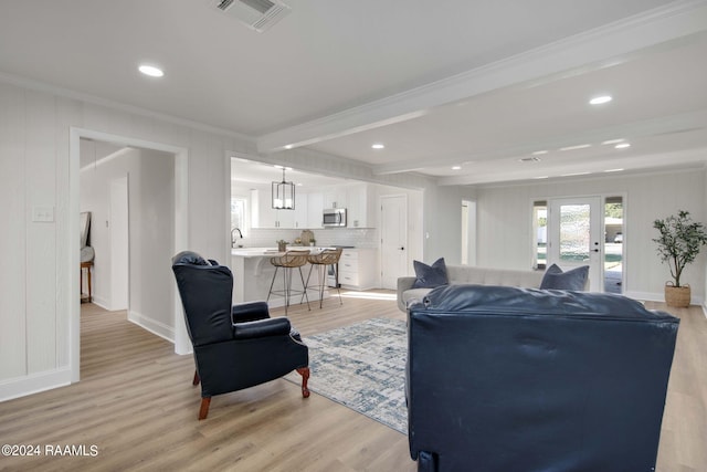 living room with french doors, beam ceiling, ornamental molding, and light wood-type flooring