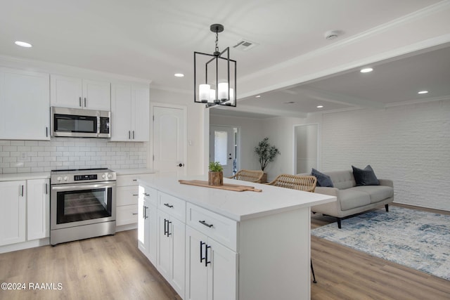 kitchen with white cabinets, light hardwood / wood-style flooring, stainless steel appliances, decorative light fixtures, and a center island