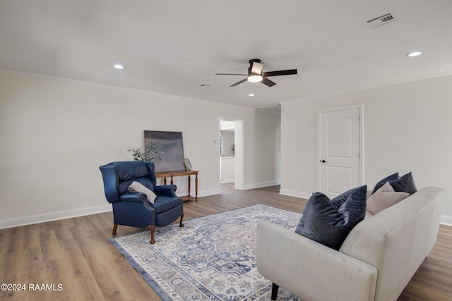 living room featuring hardwood / wood-style floors, crown molding, and ceiling fan