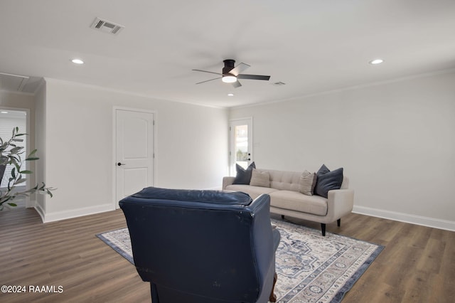 living room with dark wood-type flooring, crown molding, and ceiling fan