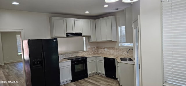 kitchen with light hardwood / wood-style floors, white cabinets, black appliances, and sink