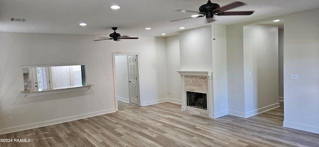 unfurnished living room with a tiled fireplace, vaulted ceiling, light hardwood / wood-style flooring, and ceiling fan