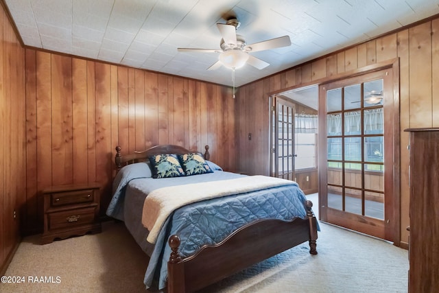 bedroom featuring wood walls, light colored carpet, and ceiling fan