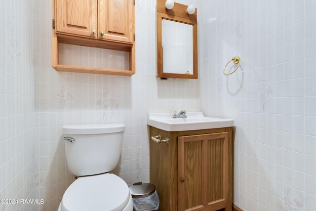 bathroom with tile walls, vanity, and toilet