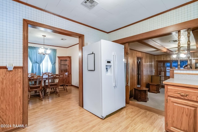 kitchen with hanging light fixtures, wood walls, ceiling fan with notable chandelier, light hardwood / wood-style floors, and white refrigerator with ice dispenser